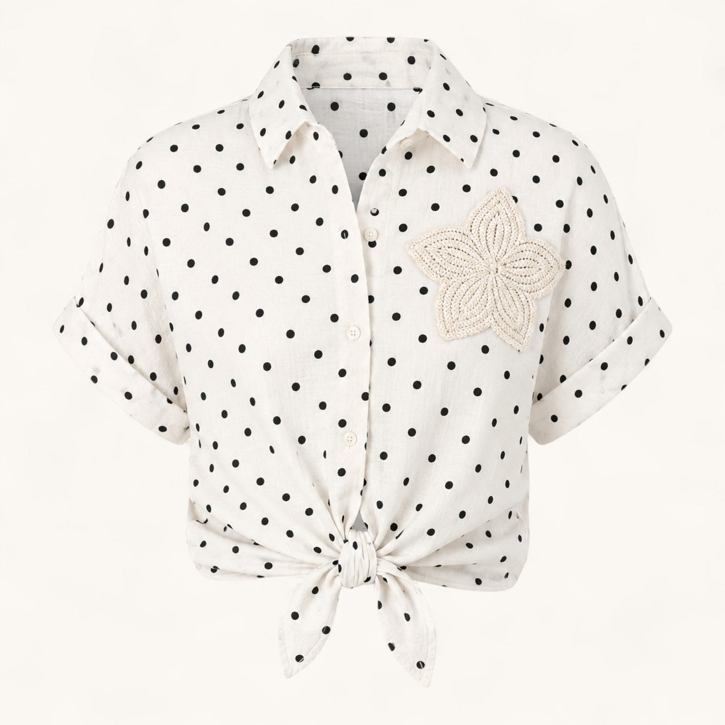 Feather & Sole white short-sleeved shirt with black polka dots, tie-front detail, and a crochet flower applique.